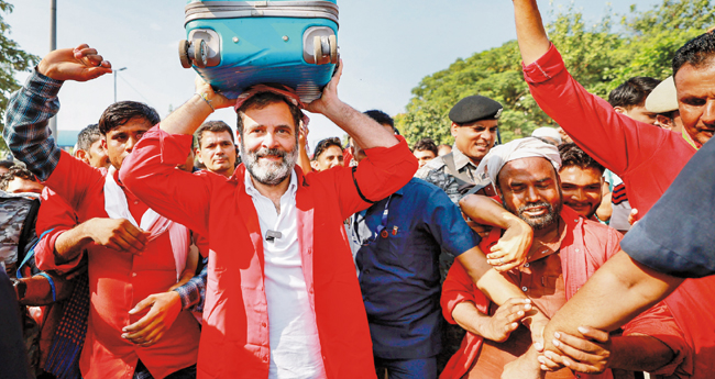 ആ​ന​ന്ദ് വി​ഹാ​ർ റെ​യി​ൽ​വേ പോ​ർ​ട്ട​ർ​മാ​ർ​ക്കൊ​പ്പം ബാ​ഗ് ത​ല​യി​ലേ​റ്റി ന​ട​ക്കു​ന്ന രാ​ഹു​ൽ ഗാ​ന്ധി.