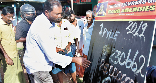 ഓ​​​ണം ബം​​​പ​​​ർ ലോ​​​ട്ട​​​റി​​​യി​​​ൽ ഒ​​​ന്നാം സ​​​മ്മാ​​​നം നേ​​​ടി​​​യ ലോ​​​ട്ട​​​റി വി​​​റ്റ വാ​​​ള​​​യാ​​​ർ ഡാം ​​​റോ​​​ഡി​​​നു സ​​​മീ​​​പ​​​ത്തെ ബാ​​​വ ലോ​​​ട്ട​​​റി ഏ​​​ജ​​​ൻ​​​സി ഉ​​​ട​​​മ ഗു​​​രു​​​സ്വാ​​​മി ക​​​ട​​​യ്ക്കു മു​​​ന്നി​​​ലെ ബോ​​​ർ​​​ഡി​​​ൽ സ​​​മ്മാ​​​നം അ​​​ടി​​​ച്ച ന​​​മ്പ​​​ർ എ​​​ഴു​​​തു​​​ന്നു.