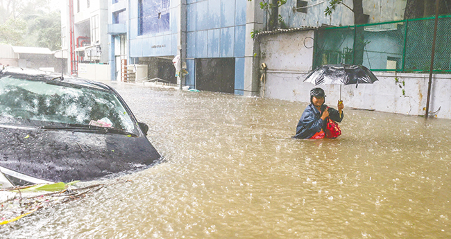 ക​ന​ത്ത മ​ഴ​യി​ൽ വെ​ള്ള​ക്കെ​ട്ട് രൂ​പ​പ്പെ​ട്ട ചെ​ന്നൈ ന​ഗ​ര​ത്തി​ൽ​നി​ന്ന് സു​ര​ക്ഷി​ത താ​വ​ള​ത്തി​ലേ​ക്ക് പോ​കു​ന്ന സ്ത്രീ.